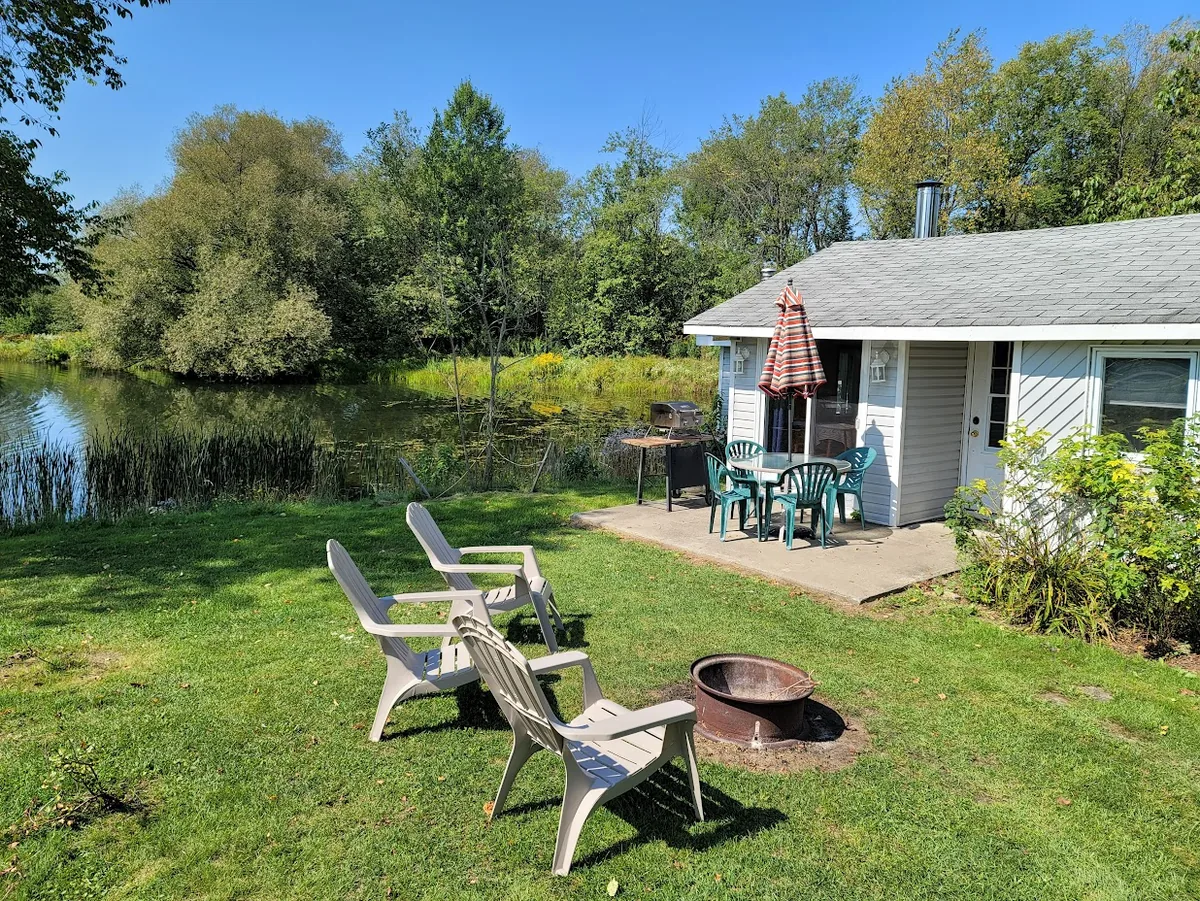 Chalet 1 avec terrasse et chaises près du petit lac du Camping de l’Estrie