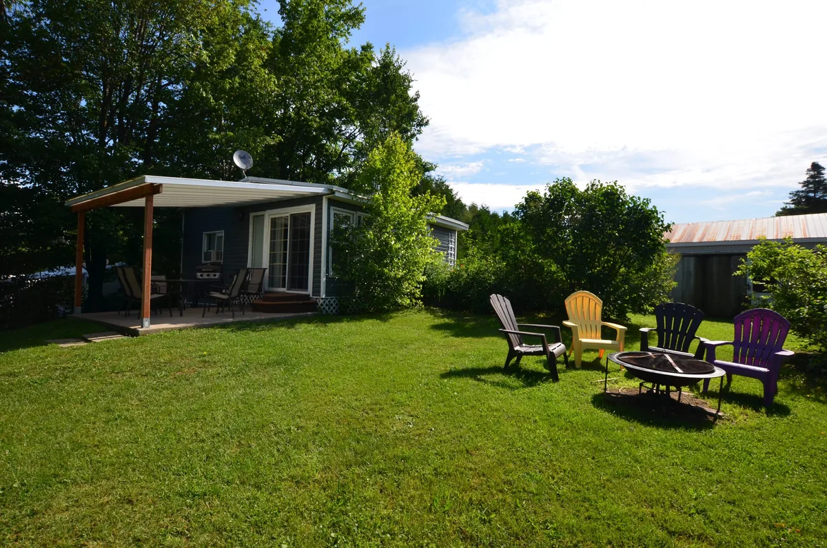 Chalet 2 et son espace extérieur avec terrasse et chaises au Camping de l’Estrie