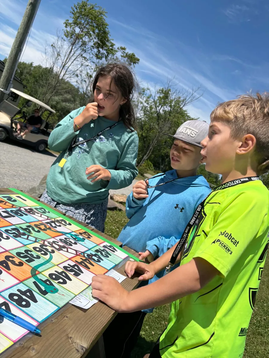Enfants autour d’un jeu géant de serpents et échelles au camping