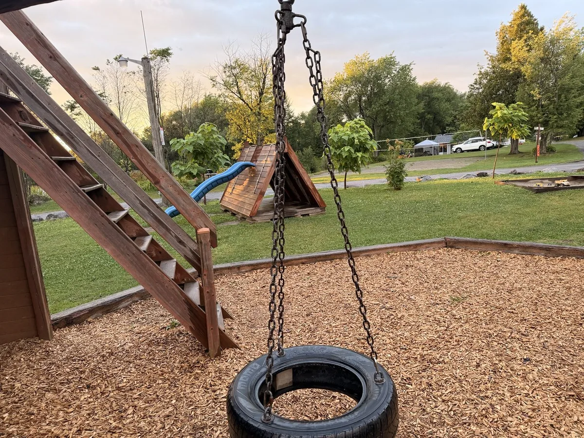 Balançoire en pneu et structures de jeu en bois au camping