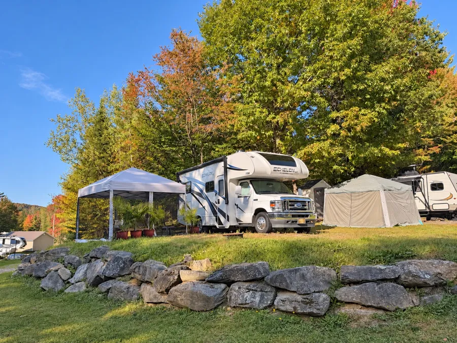 Emplacement de camping avec véhicule récréatif, pelouse et arbres